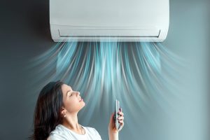 A girl stands under air conditioning and a stream of fresh cold air against a gray wall - Sugar Land Mold Remediation