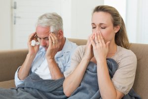 Sick couple sitting on the couch under a blanket - Symptoms of Mold Sickness